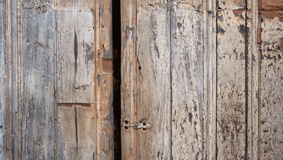 Closeup of a vintage wooden door with rustic texture, showcasing aged wood and peeling paint.