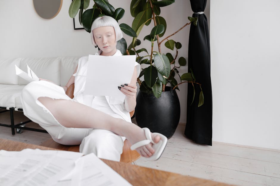 Stylish woman in white reading documents in a contemporary living space.