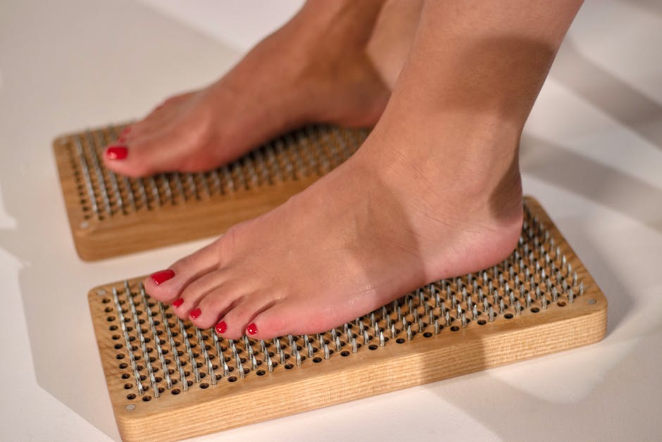 Feet with red pedicure standing on wooden acupressure boards for health benefits.