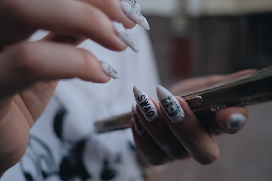Close-up image showcasing detailed nail art on hands holding a smartphone. Modern and trendy design.