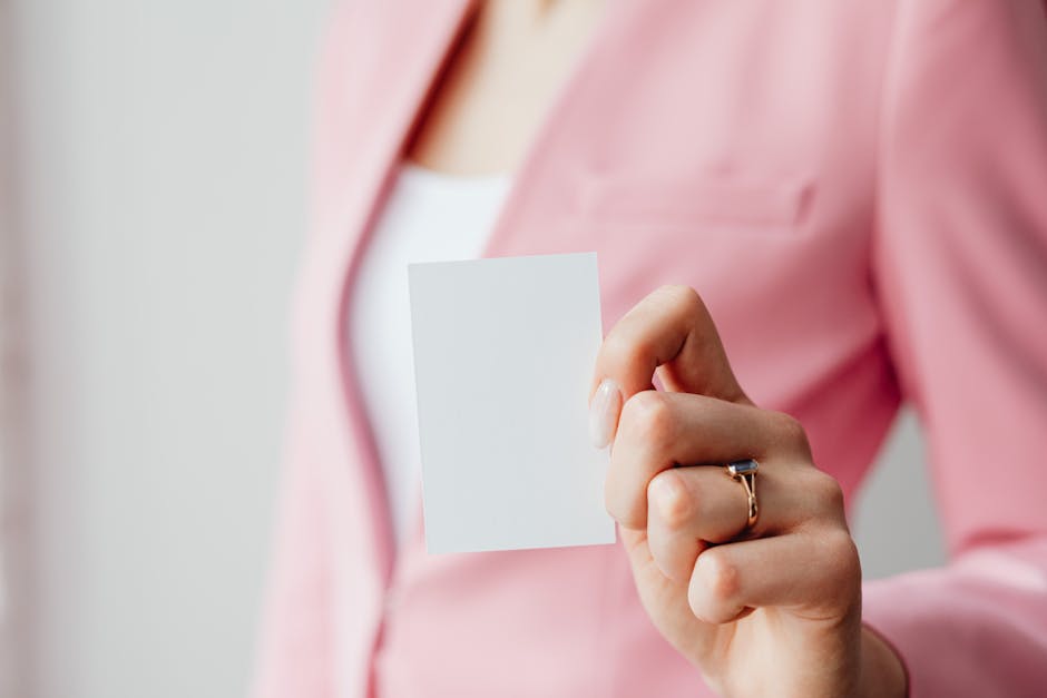 Close-up of a woman's hand holding a blank business card with a blurred background for design mockup.