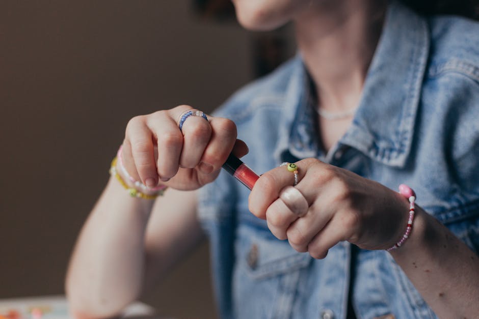 A detailed close-up of a woman carefully holding and twisting a lipstick tube.