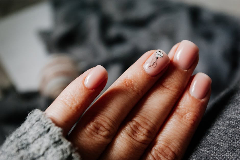 Close-up of a woman's elegant manicure featuring a jellyfish design on soft pastel nails.